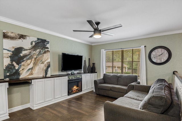 living area with dark wood finished floors, ornamental molding, a ceiling fan, and a warm lit fireplace