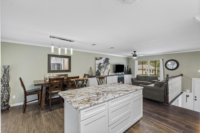 kitchen with dark wood-style floors, white cabinets, a ceiling fan, light stone countertops, and decorative light fixtures