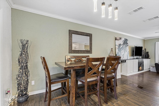 dining area with dark wood-style floors, ornamental molding, a textured wall, baseboards, and a chandelier