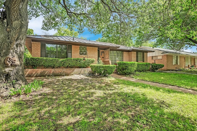 1225 Oak Meadows Dr, Dallas, TX 75232 - single story home featuring brick siding, a standing seam roof, a front yard, and metal roof