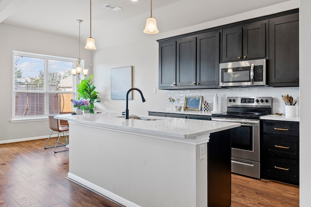 125 Singleton Dr, Royse City, TX 75189 - kitchen featuring stainless steel appliances, a sink, decorative backsplash, a center island with sink, and wood finished floors