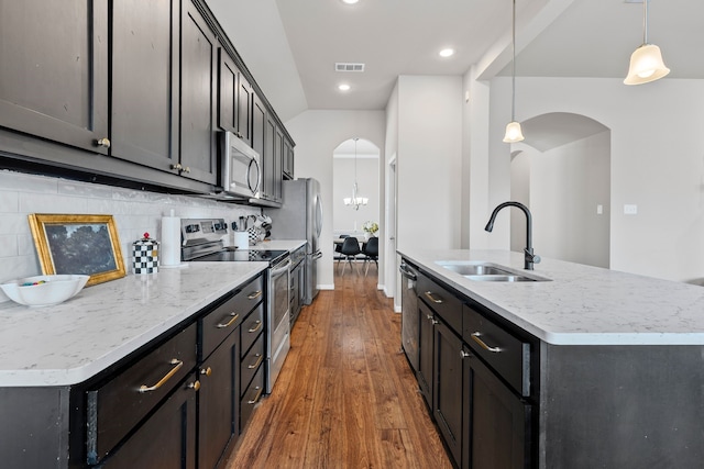 125 Singleton Dr, Royse City, TX 75189 - kitchen with stainless steel appliances, a sink, arched walkways, an island with sink, and wood-type flooring