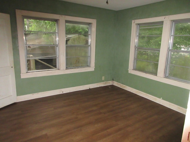 spare room with baseboards and dark wood finished floors