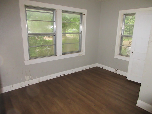 spare room with baseboards, plenty of natural light, and dark wood-style flooring