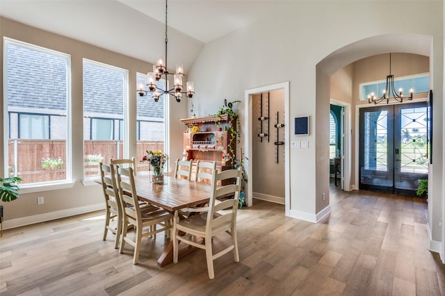 1305 Limestone Ridge Rd, Mansfield, TX 76063 - dining space with a chandelier, arched walkways, vaulted ceiling, light wood-style flooring, and baseboards