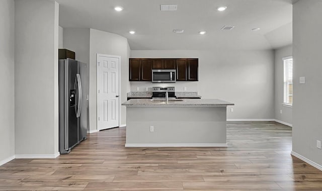 7025 Canadian Dr, Waco, TX 76633 - kitchen with stainless steel appliances, light wood finished floors, vaulted ceiling, baseboards, and a center island with sink