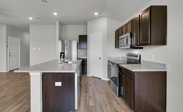 7025 Canadian Dr, Waco, TX 76633 - kitchen featuring stainless steel appliances, a sink, dark brown cabinets, wood finished floors, and an island with sink