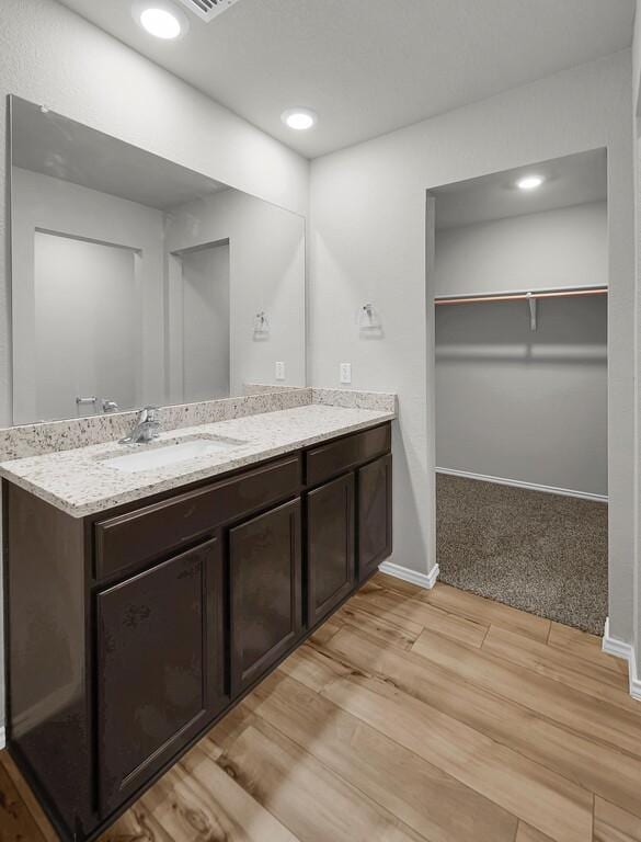 7025 Canadian Dr, Waco, TX 76633 - bathroom featuring wood finished floors, vanity, baseboards, a spacious closet, and recessed lighting