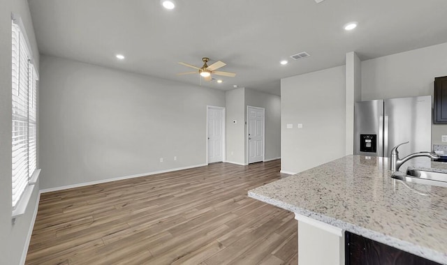 7025 Canadian Dr, Waco, TX 76633 - kitchen featuring stainless steel fridge, a sink, ceiling fan, wood finished floors, and light stone countertops