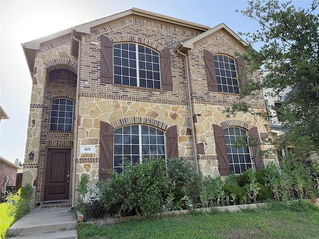 french country home with brick siding and stone siding