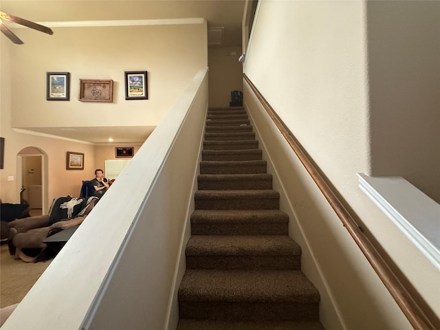 stairs with ceiling fan, arched walkways, and carpet flooring