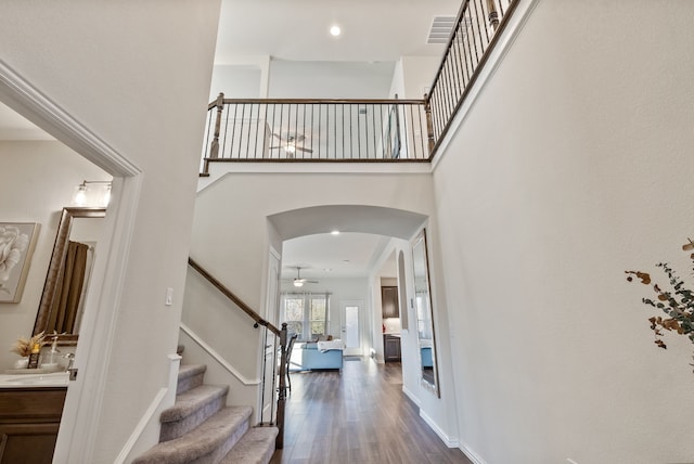 9517 Sunset Ln, Oak Point, TX 75068 - foyer featuring dark wood finished floors, stairs, arched walkways, a ceiling fan, and a towering ceiling