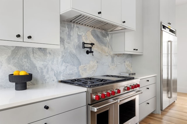 3943 Hawthorne Unit 102, Dallas, TX 75219 - kitchen featuring high quality appliances, tasteful backsplash, light countertops, white cabinets, and extractor fan