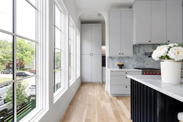 3943 Hawthorne Unit 102, Dallas, TX 75219 - kitchen featuring light countertops, tasteful backsplash, light wood finished floors, and arched walkways