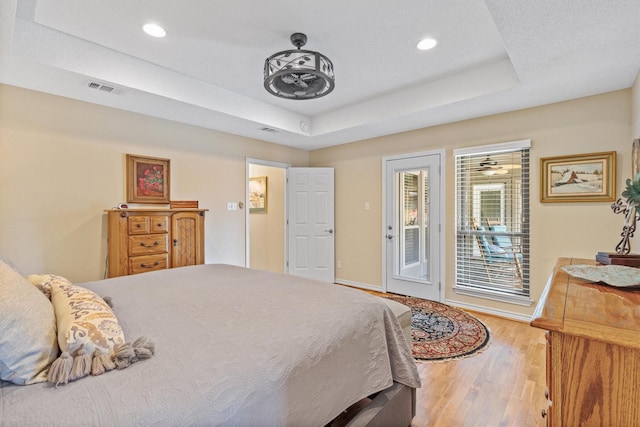 bedroom with access to outside, a raised ceiling, baseboards, wood finished floors, and recessed lighting