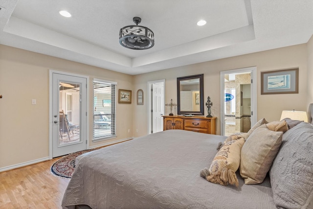 bedroom featuring a raised ceiling, light wood-style flooring, baseboards, access to exterior, and recessed lighting