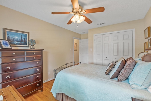 bedroom featuring light wood finished floors, a closet, a ceiling fan, and baseboards