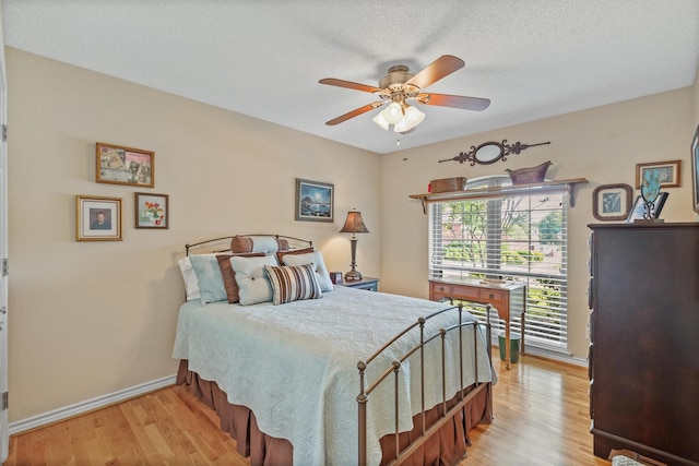 bedroom with light wood-style flooring, baseboards, a ceiling fan, and a textured ceiling