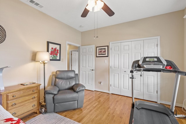 exercise room with ceiling fan, light wood-style flooring, and baseboards