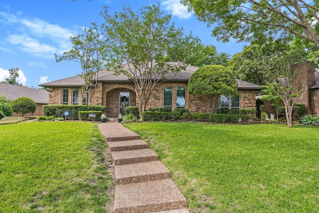 view of front facade featuring a front lawn, brick siding, and roof with shingles