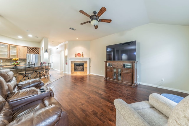 living area with ceiling fan, wood finished floors, a tile fireplace, baseboards, and lofted ceiling