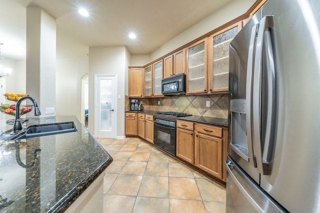 kitchen with black appliances, a sink, light tile patterned floors, brown cabinets, and backsplash