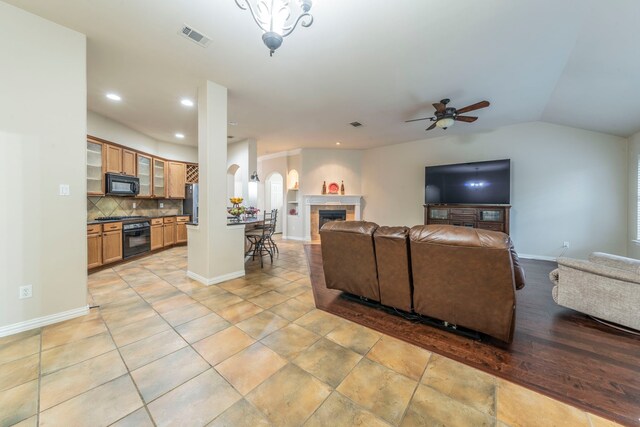 living area featuring a ceiling fan, recessed lighting, a fireplace, baseboards, and lofted ceiling