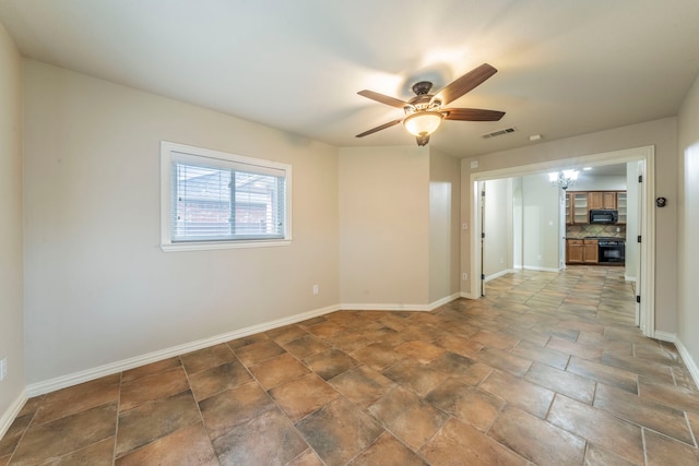spare room with baseboards, a ceiling fan, and stone finish floors