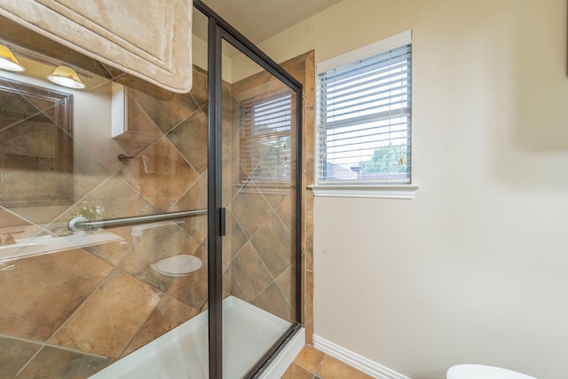 full bathroom featuring a shower stall, tile patterned floors, toilet, and baseboards