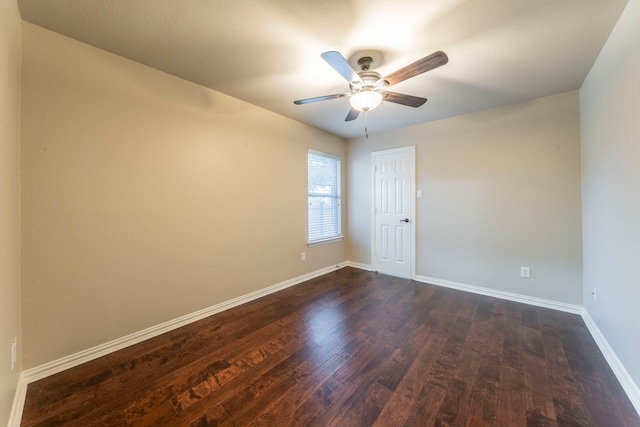 unfurnished room featuring dark wood-style flooring, a ceiling fan, and baseboards