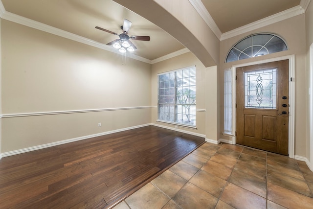 entryway featuring a ceiling fan, crown molding, baseboards, wood finished floors, and arched walkways