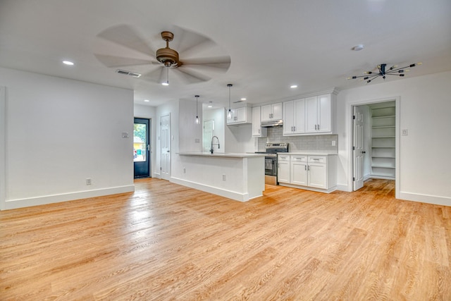 kitchen with stainless steel range with electric cooktop, light wood-type flooring, a sink, white cabinets, and recessed lighting