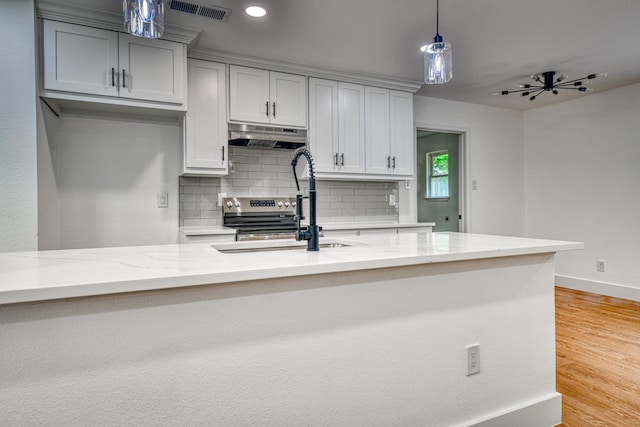 kitchen with under cabinet range hood, backsplash, a sink, light stone countertops, and recessed lighting