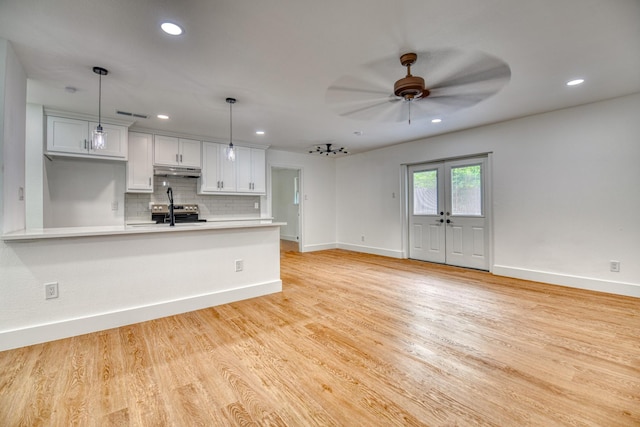 kitchen featuring under cabinet range hood, a ceiling fan, light countertops, baseboards, and decorative backsplash