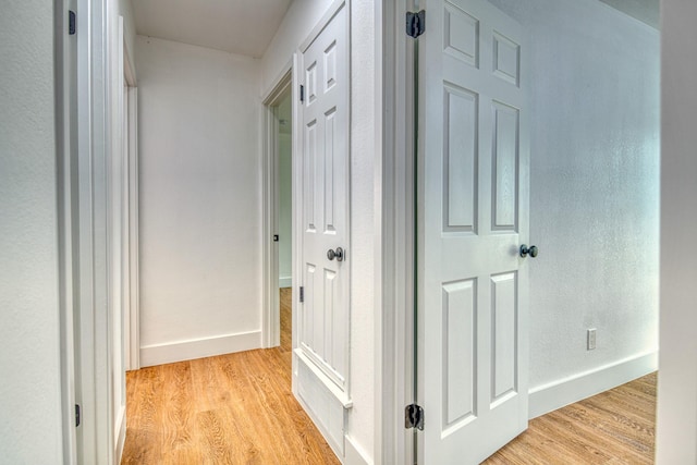 corridor with light wood-style flooring and baseboards