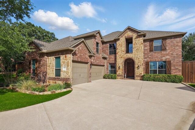 3002 Spring Hill Ln, Highland Village, TX 75077 - view of front facade with stone siding, concrete driveway, a shingled roof, an attached garage, and brick siding