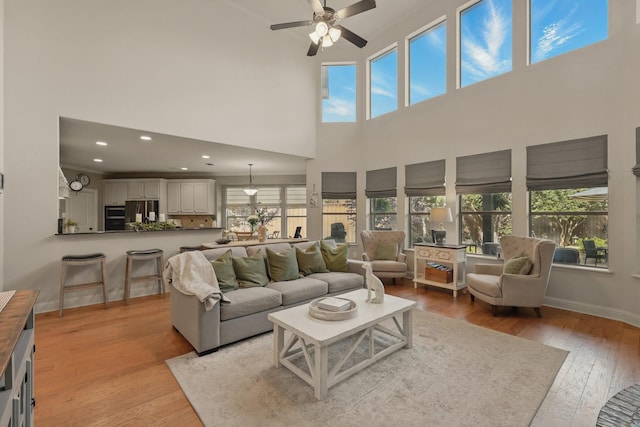 3002 Spring Hill Ln, Highland Village, TX 75077 - living room featuring healthy amount of natural light, a ceiling fan, light wood-style flooring, a towering ceiling, and baseboards