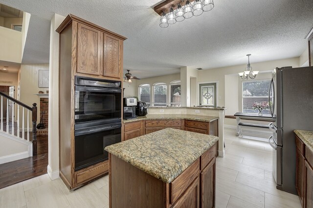 4205 English Ivy Dr, Mckinney, TX 75070 - kitchen with freestanding refrigerator, a peninsula, light stone counters, ceiling fan, and a chandelier