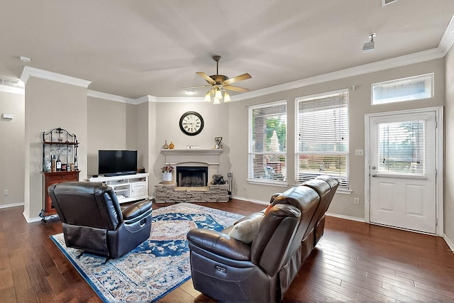 living area featuring dark wood-type flooring, a fireplace, ornamental molding, a ceiling fan, and healthy amount of natural light
