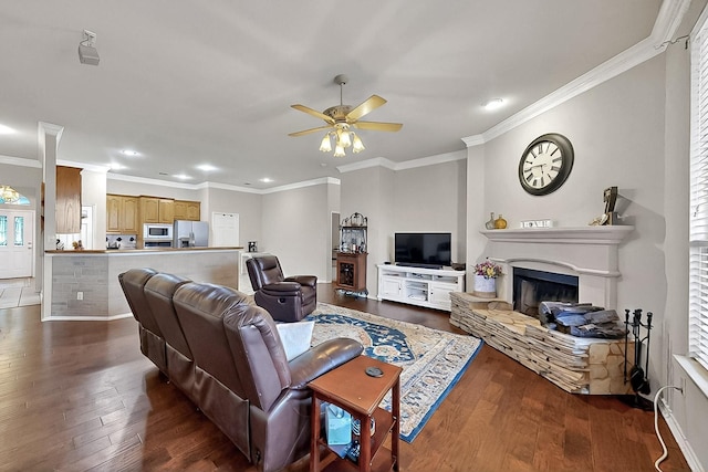 living room with a ceiling fan, ornamental molding, hardwood / wood-style flooring, recessed lighting, and a fireplace with raised hearth