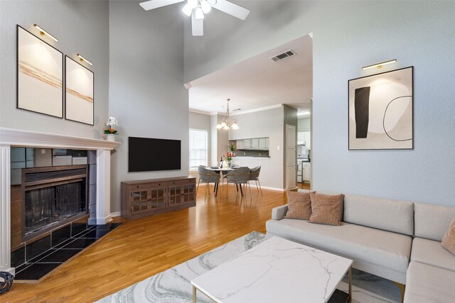 6000 Auburndale Ave Unit E, University Park, TX 75205 - living area featuring wood finished floors, a chandelier, a tiled fireplace, a ceiling fan, and ornamental molding