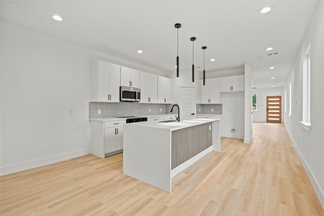 2534 Pennsylvania Ave, Dallas, TX 75215 - kitchen featuring stainless steel microwave, recessed lighting, decorative backsplash, light wood-style flooring, and white cabinets