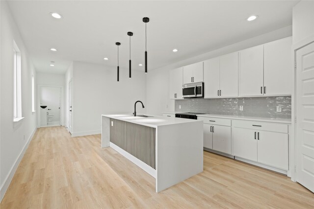 2534 Pennsylvania Ave, Dallas, TX 75215 - kitchen featuring stainless steel microwave, decorative backsplash, light wood-type flooring, an island with sink, and recessed lighting