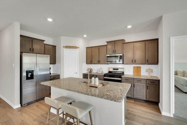 1403 Blossom Court Dr, Princeton, TX 75407 - kitchen featuring stainless steel appliances, a sink, light wood finished floors, light stone counters, and tasteful backsplash