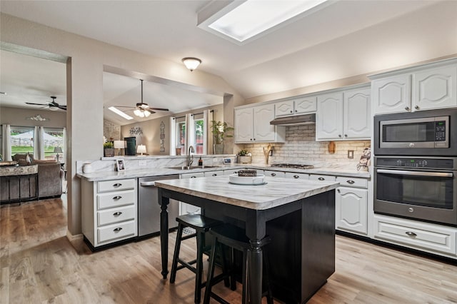 2630 Argyle Shore Dr, Rockwall, TX 75087 - kitchen featuring appliances with stainless steel finishes, lofted ceiling, a peninsula, a breakfast bar, and decorative backsplash