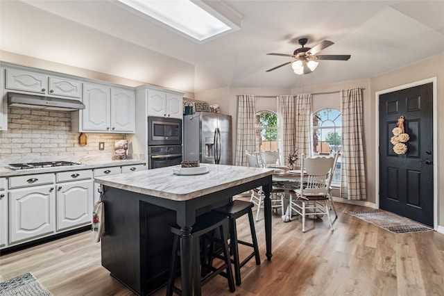 2630 Argyle Shore Dr, Rockwall, TX 75087 - kitchen featuring stainless steel appliances, light countertops, a ceiling fan, a kitchen breakfast bar, and backsplash