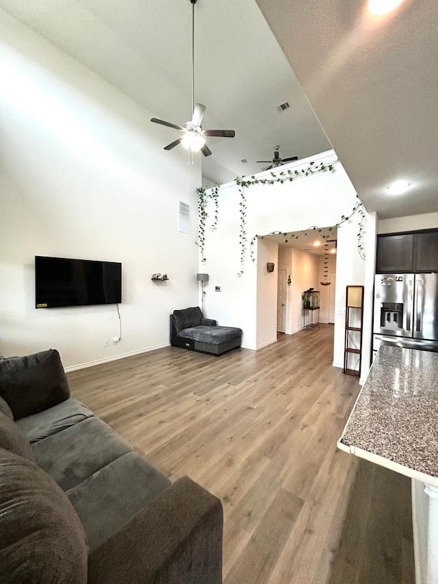 7425 Bledington Ln, Mckinney, TX 75071 - living area with a ceiling fan, a towering ceiling, light wood-style flooring, and baseboards