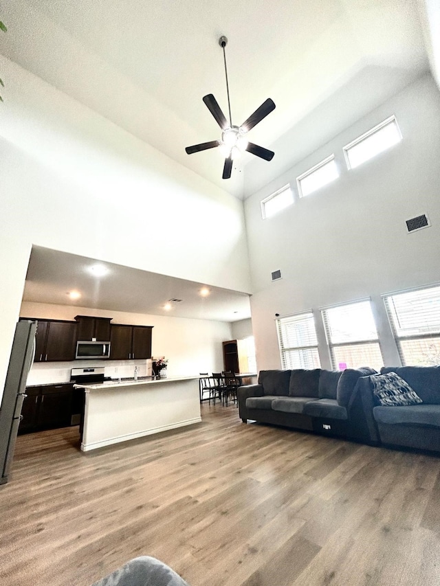 7425 Bledington Ln, Mckinney, TX 75071 - living area with light wood-type flooring, ceiling fan, healthy amount of natural light, and a high ceiling