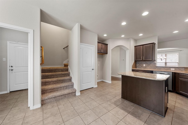 5541 Wisdom Ct, Waco, TX 76708 - kitchen with dishwasher, dark brown cabinetry, a kitchen island, arched walkways, and tasteful backsplash