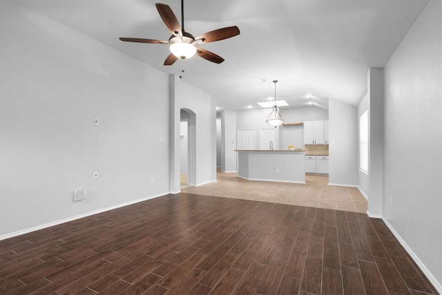 3432 Beatriz Dr, Denton, TX 76207 - unfurnished living room featuring arched walkways, a ceiling fan, lofted ceiling, light wood-style floors, and baseboards